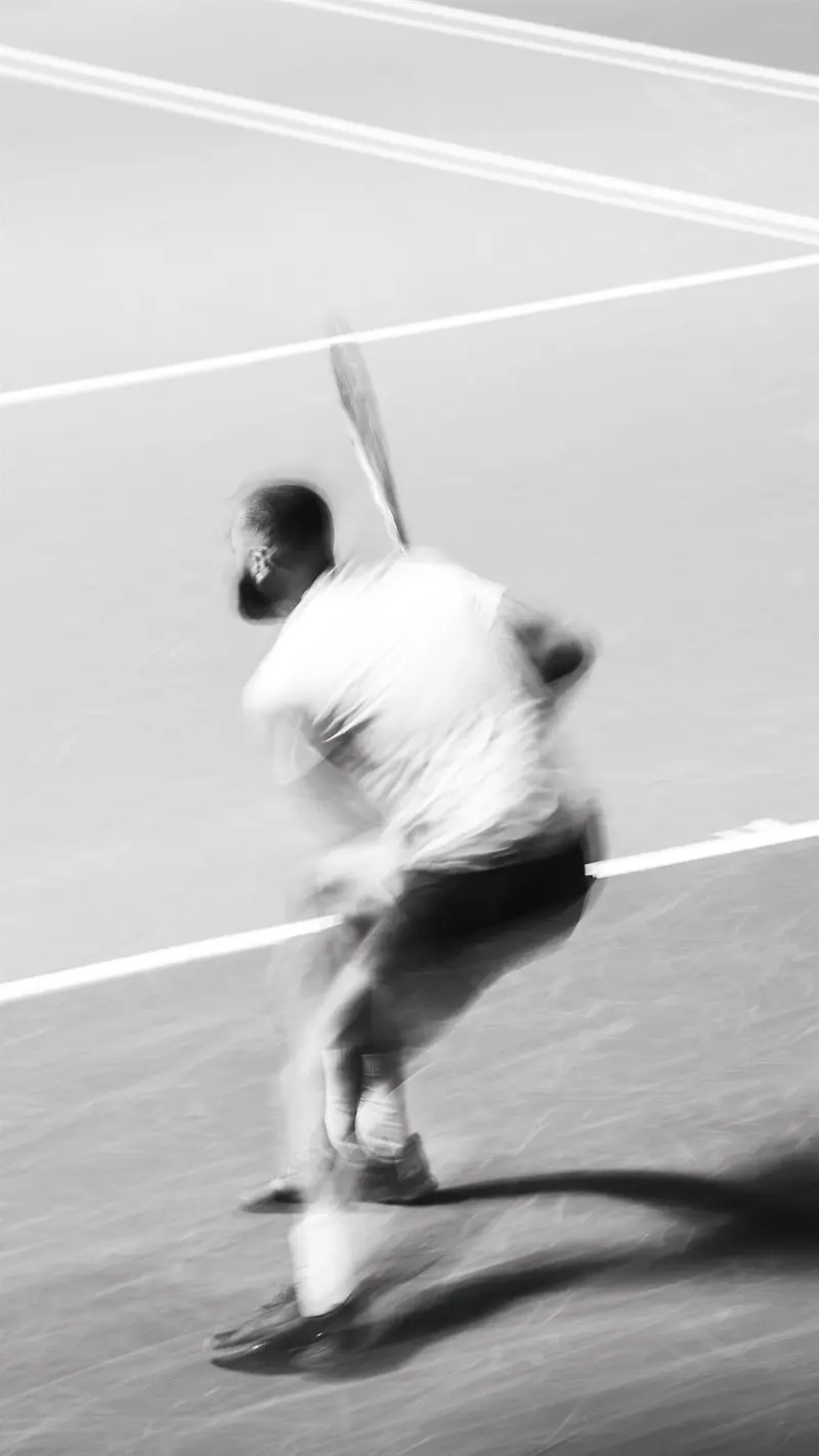 Joueur de tennis en pleine frappe, effet de filé en noir et blanc
